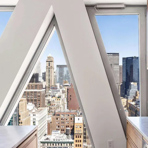 Detail of the facade’s diagonal lattice columns framing the Midtown skyline from a kitchen at Midtown Luxury Residences, 30 East 31 Street, New York City, interior design by Alexandra Peck Design