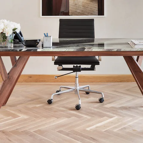 Detail: walnut and glass reception desk with a black leather chair on herringbone oak floors in the reception at Flatiron Workplace, 3 East 28th Street, New York City, interior design by Alexandra Peck Design
