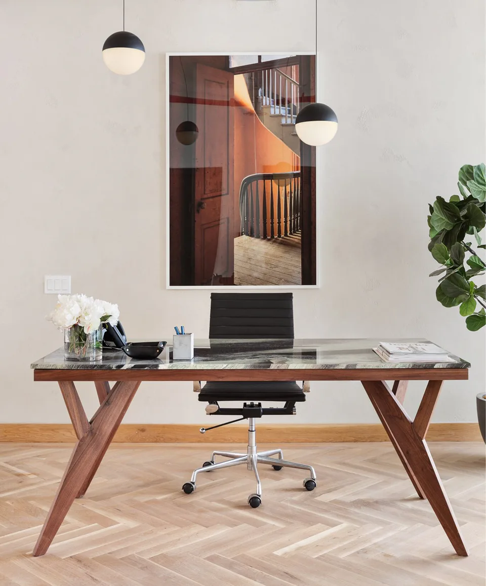 Reception desk in walnut and glass with a black leather chair, globe pendants and a framed photograph on herringbone oak floors at Flatiron Workplace, 3 East 28th Street, New York City, interior design by Alexandra Peck Design