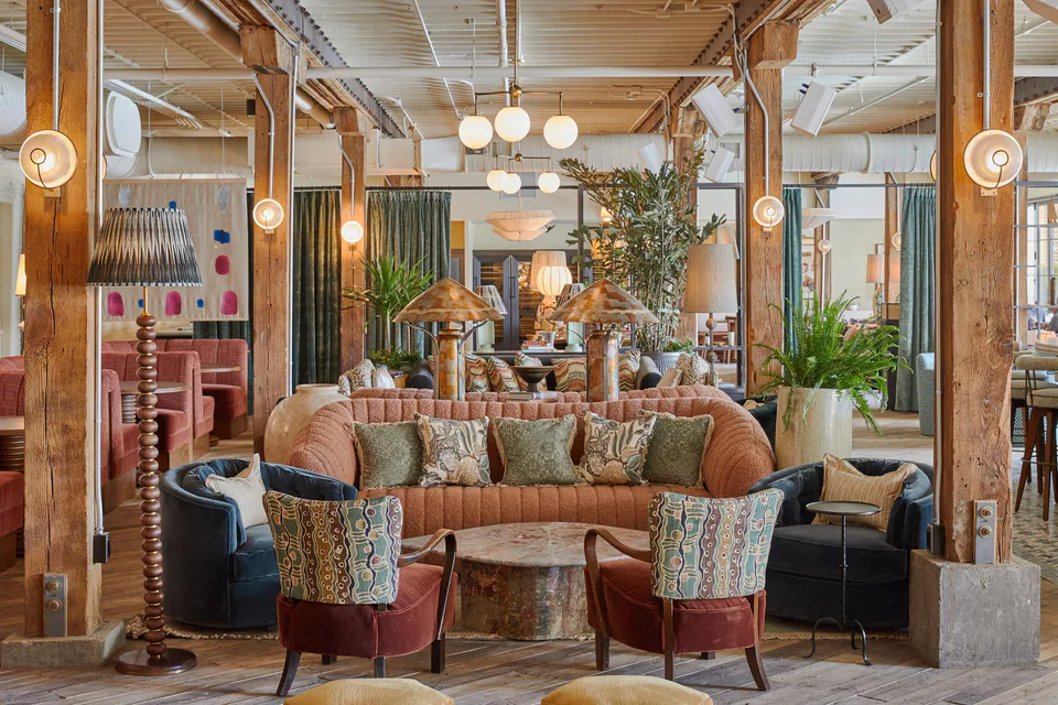 Club Cecconi’s lounge with a curved terracotta sofa, patterned armchairs and timber columns at Soho House Nashville, Nashville, Tennessee, interior design by Alexandra Peck Design