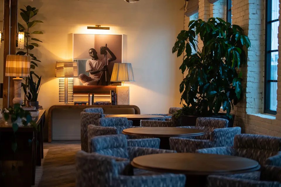 The Sock Room lounge with patterned blue armchairs around wooden tables, table lamps and a framed portrait photograph at Soho House Nashville, Nashville, Tennessee, interior design by Alexandra Peck Design
