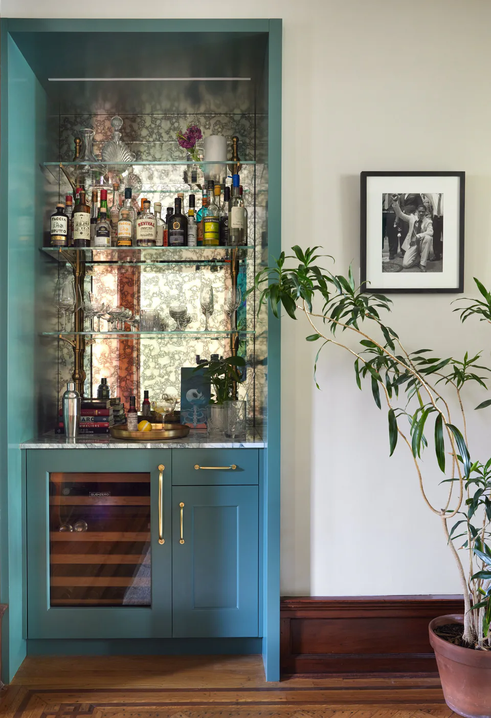 Dry bar with teal-painted cabinetry, antique mirror and open glass shelving for libations and glassware in the cocktail lounge at the Prospect Heights Brownstone, Brooklyn, New York, interior design by Alexandra Peck Design