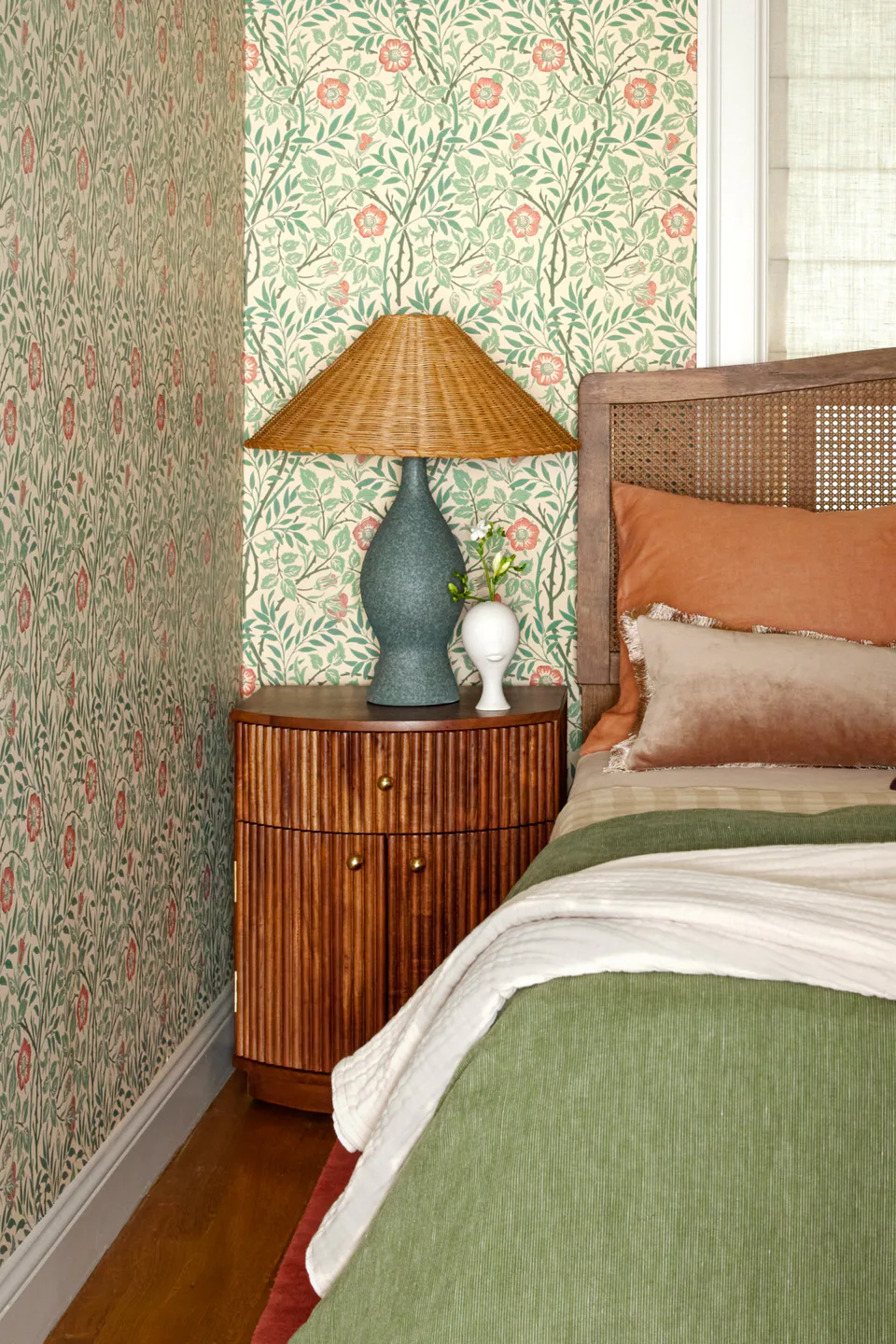 Guest bedroom with Morris & Co. floral wallpaper, a wicker headboard, sage bedding and a woven-shade table lamp at the Prospect Heights Brownstone, Brooklyn, New York, interior design by Alexandra Peck Design