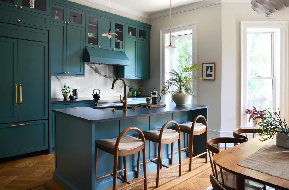 Teal-painted shaker-paneled kitchen with an island, scalloped porcelain pendants and original parquet floors at the Prospect Heights Brownstone, Brooklyn, New York, interior design by Alexandra Peck Design