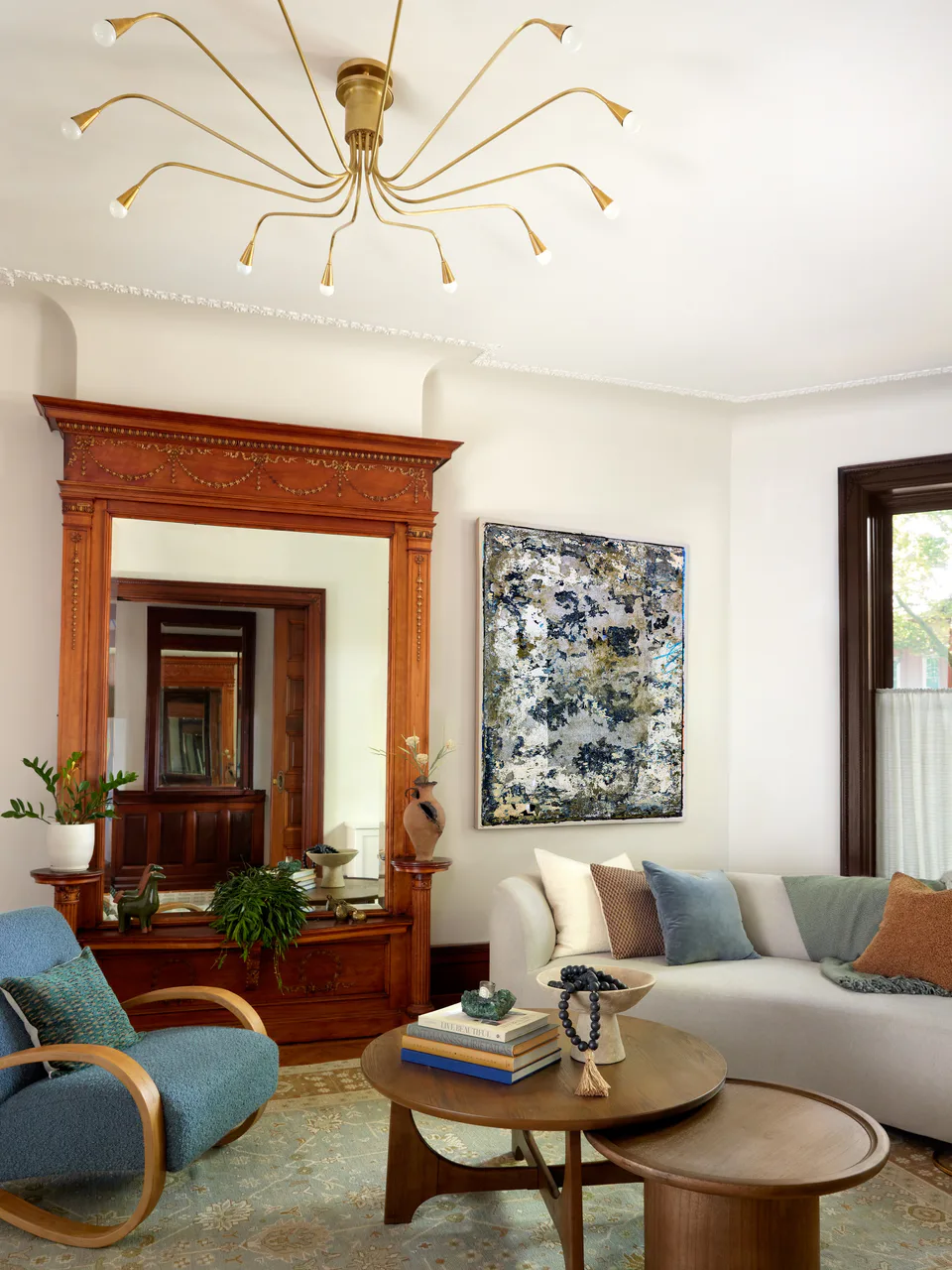 Parlor living room beneath a bespoke brass chandelier, with a curved sofa and the restored built-in mirror at the Prospect Heights Brownstone, Brooklyn, New York, interior design by Alexandra Peck Design