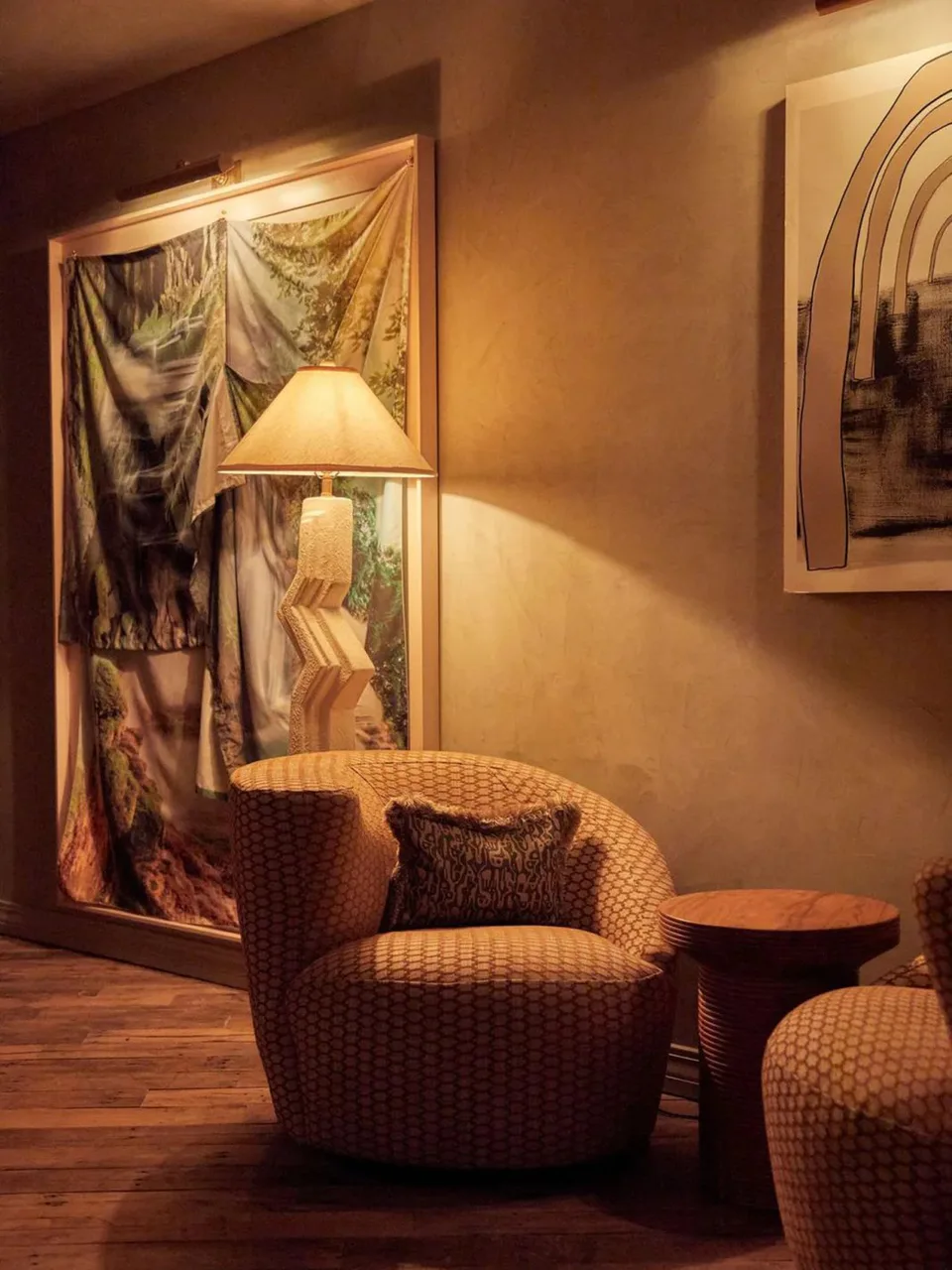 Round upholstered armchair beneath a pleated lamp and a framed textile artwork at Club Cecconi’s, Soho House Nashville, Nashville, Tennessee, interior design by Alexandra Peck Design