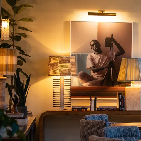 Detail: framed portrait photograph under a picture light between pleated table lamps in The Sock Room at Soho House Nashville, Nashville, Tennessee, interior design by Alexandra Peck Design