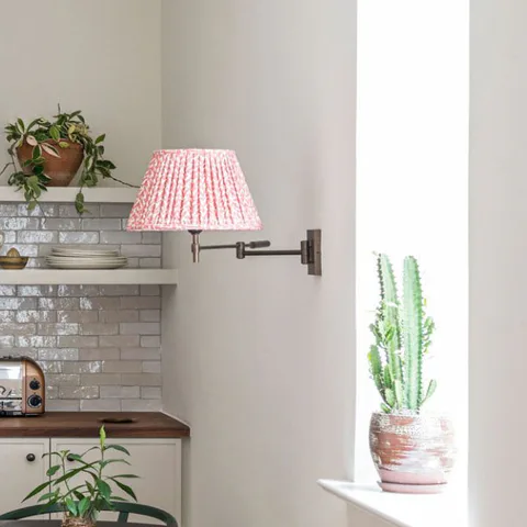 Detail: pink pleated wall sconce and a potted cactus on the kitchen windowsill at The Pinch Hotel, Charleston, South Carolina, interior design by Alexandra Peck Design