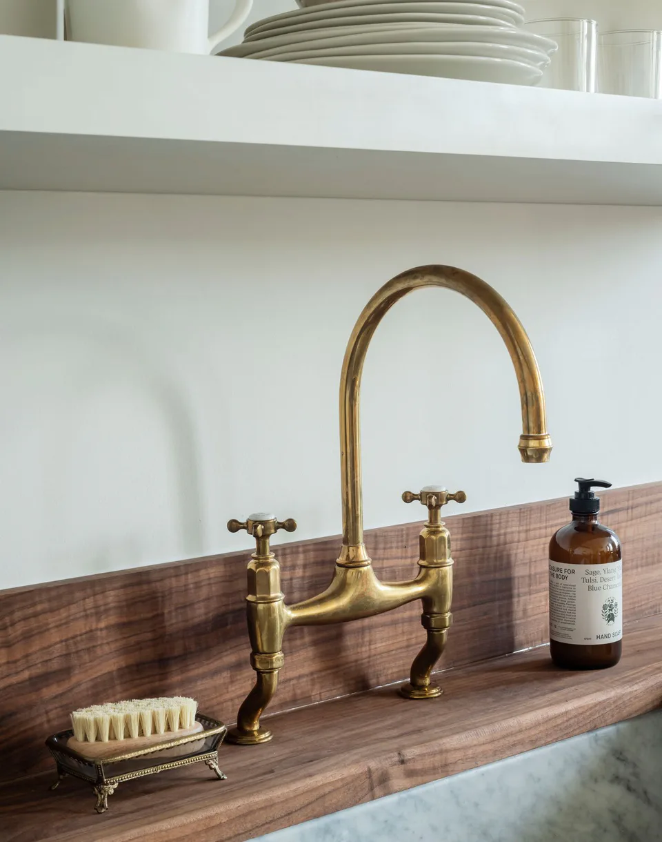 Unfinished brass deVOL bridge faucet on a walnut ledge above a marble sink at The Pinch Hotel, Charleston, South Carolina, interior design by Alexandra Peck Design
