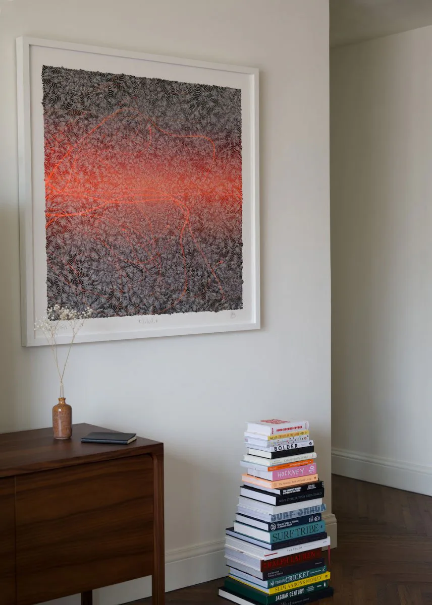 Living room corner with a red abstract artwork above a walnut chest and a stack of books at The Pinch Hotel, Charleston, South Carolina, interior design by Alexandra Peck Design