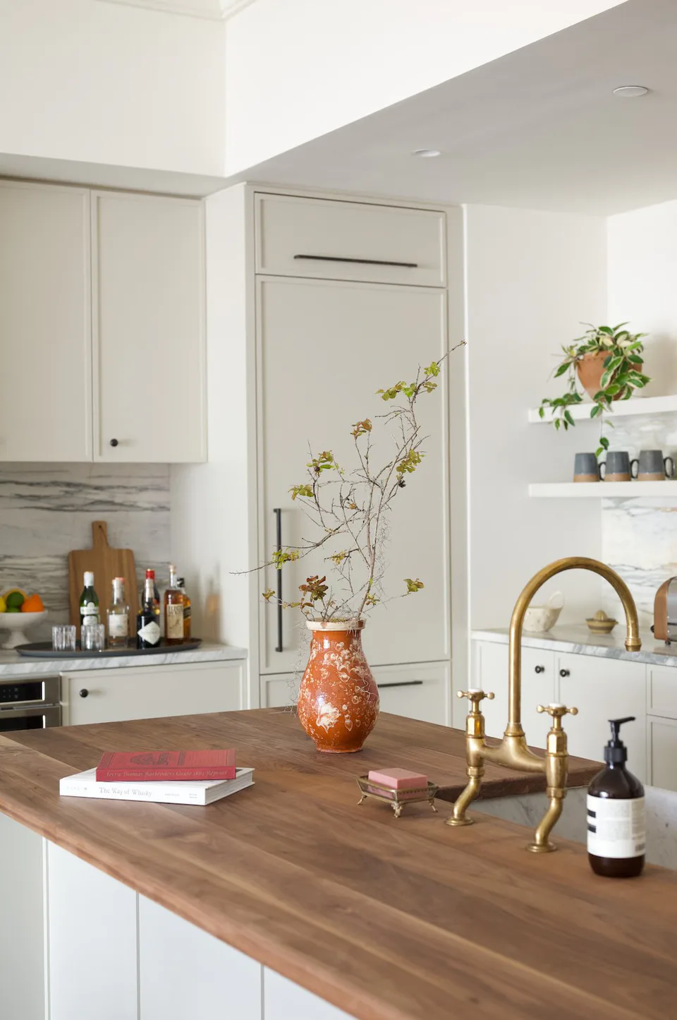 Suite kitchen with a walnut counter, a brass bridge faucet and open shelving at The Pinch Hotel, Charleston, South Carolina, interior design by Alexandra Peck Design